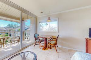 a dining room with a table and chairs and a balcony at Islander on the Beach 304 in Kapaa