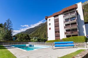 a building with a swimming pool in front of a building at Résidence Grands Montets 221 ski in-ski out - Happy Rentals in Chamonix