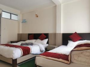 sypialnia z 2 łóżkami z czerwoną i białą pościelą w obiekcie Om Bramha Hotel w Katmandu