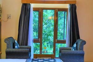 two chairs in front of a glass door with a window at The Den Corbett Resort in Dhikala Zone