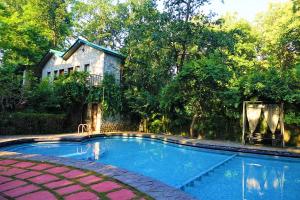 a swimming pool in front of a house at The Den Corbett Resort in Dhikala Zone