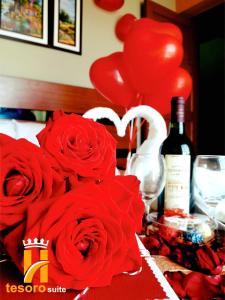 una mesa con rosas rojas y una botella de vino y globos en Tesoro Suite en Tacna