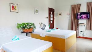 een hotelkamer met 2 bedden en een televisie bij Heart Hotel and Services in Dumaguete