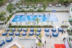 an overhead view of a pool with tables and blue and white umbrellas at Sangkahak Mith Hotel in Kep
