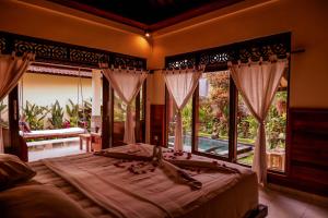 a bedroom with a large bed and a large window at Jagi Villa in Ubud
