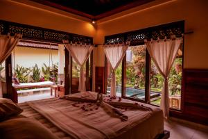 ein Schlafzimmer mit einem großen Bett und einem großen Fenster in der Unterkunft Jagi Villa in Ubud