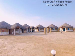 a row of houses with thatched roofs in a field at Kutir Craft Village Resort in Bherandiāla