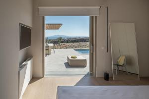 a bedroom with a view of a pool and a television at Aesthesis Boutique Villa Trace in Fira