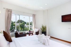 a bedroom with a white bed and a large window at Kanchanaburi City Hotel in Kanchanaburi