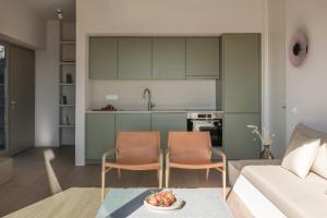 a living room with two chairs and a kitchen at Aesthesis Boutique Villa Trace in Fira