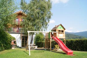 a playground in front of a house with a slide at Ferienhaus mit Panoramaausblick und Sauna - 3 SZ in Pöllauberg