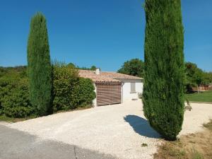 une maison avec un garage et un grand arbre dans l'établissement La Petite Maison Dans Les Vignes, à Chamaret