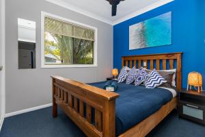 Un dormitorio con una cama con paredes azules y una ventana en KiteSurf 1770 Beach House en Agnes Water