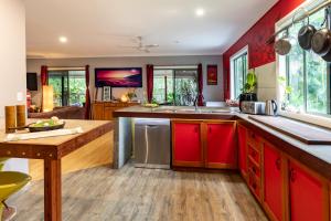 cocina con armarios rojos y mesa de madera en KiteSurf 1770 Beach House en Agnes Water