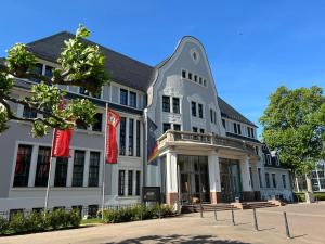 a large white building with flags in front of it at Kasino Hotel in Leverkusen