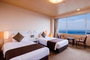 two beds in a hotel room with a view of the ocean at KAMENOI HOTEL Yaizu in Yaizu