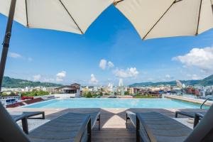a pool on the roof of a building with umbrellas at LullaBella Hotel Patong,Nanai Road in Patong Beach