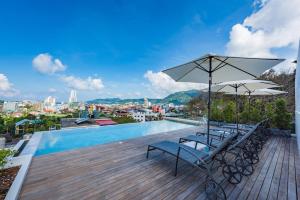 a pool with chairs and umbrellas on a deck at LullaBella Hotel in Patong Beach