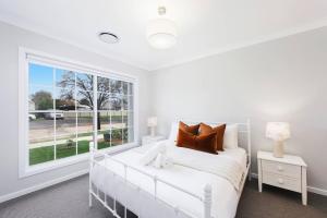 1 dormitorio con cama blanca y ventana grande en A Refreshing Mudgee Getaway at Felicitys on Court, en Mudgee