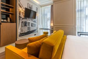 a living room with a yellow couch and a tv at Eurostars Lisboa Baixa in Lisbon