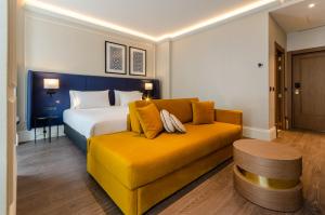 a bedroom with a bed and a yellow couch at Eurostars Lisboa Baixa in Lisbon
