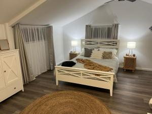 1 dormitorio con 1 cama blanca y 2 lámparas en Billabong Cottage, en Oxley Island