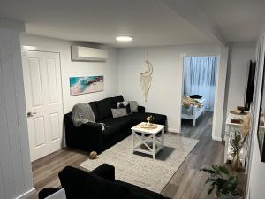 sala de estar con sofá negro y mesa en Billabong Cottage, en Oxley Island