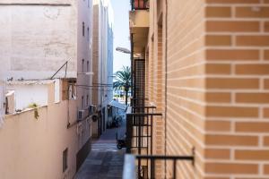 un callejón entre dos edificios con una palmera a lo lejos en Excelente apartamento en 2ª línea de playa. WIFI!, en Puerto Sagunto