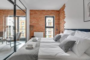 a large white bed in a room with a brick wall at Downtown Apartments Aura III in Gdańsk