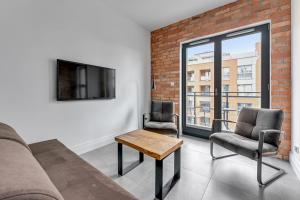 a living room with a couch and two chairs and a tv at Downtown Apartments Aura III in Gdańsk