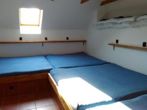 2 Betten in einem kleinen Zimmer mit blauer Bettwäsche in der Unterkunft Apartmán na farmě u koní in Milešov