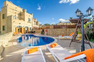 - une piscine avec des chaises longues et une balançoire dans l'établissement Rebbiegha Holiday Home, à Qala