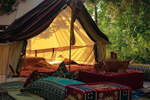 ein Zelt mit Kissen und einem Tisch davor in der Unterkunft Butterfly Valley Beach Glamping with Food in Oludeniz