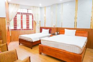 a bedroom with two beds and a chair at Nhu Y Hotel in Tuy Hoa
