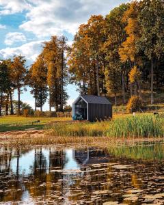 a small black building sitting next to a body of water at PullanHouse Laima - small and cosy lakeside holiday house in Alūksne
