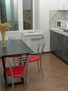 una cocina con mesa negra y sillas rojas en Уютная и просторная квартира в 50 метрах от городского парка en Petropavlovsk
