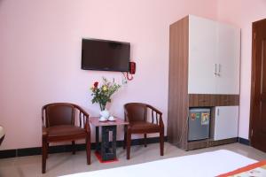 een woonkamer met 2 stoelen, een tafel en een tv bij Ban Mai Hotel 66 in Phan Thiet