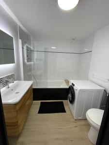 a bathroom with a tub and a sink and a washing machine at Chalet La joue du Loup in Le Dévoluy
