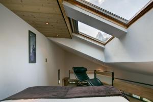 a bedroom with a bed and a window and a chair at Chalet Abacus in Zermatt