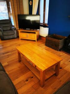 uma sala de estar com uma mesa de café em madeira e uma televisão de ecrã plano em Picturesque Riverside Home em Cahersiveen
