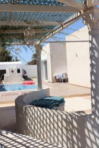 un patio con mesa, sillas y una lámpara de araña en Magnifique villa avec piscine, en Djerba