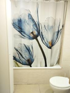 baño con cortina de ducha con una flor azul en Cozy flat with terrace en Palamós