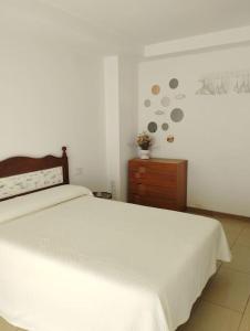 a bedroom with a white bed and a wooden dresser at Cozy flat with terrace in Palamós