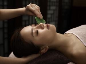 a woman laying on a bed with a brush in her face at Langham Place Guangzhou - Walking distance to Canton Fair in Guangzhou