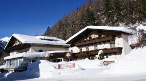 un edificio cubierto de nieve frente a una montaña en Berghotel Hois, en Heiligenblut