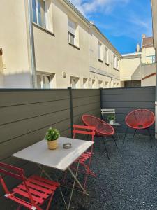 d'une terrasse avec des chaises rouges, une table et une clôture. dans l'établissement Le Sacré - CENTRE - Cour privative - PARKING, à Reims