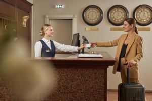 una mujer estrechando la mano de un cajero en una oficina en Ratonda Centrum Hotels, en Vilna