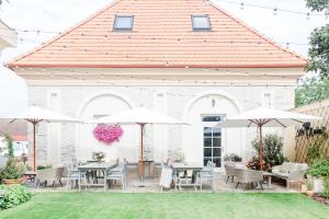 eine Terrasse mit Tischen, Stühlen und Sonnenschirmen in der Unterkunft Na Kmíně in Obříství