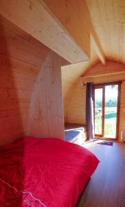 a bedroom with a red bed in an attic at Les Roulottes de la Ferme des Chanaux in Saint-Julien-dʼAnce