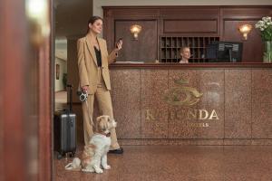 Eine Frau steht mit einem Hund neben einer Bar. in der Unterkunft Ratonda Centrum Hotels in Vilnius